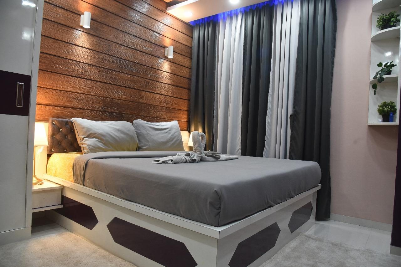 A bedroom with a slatted wood feature wall and warm wall lights